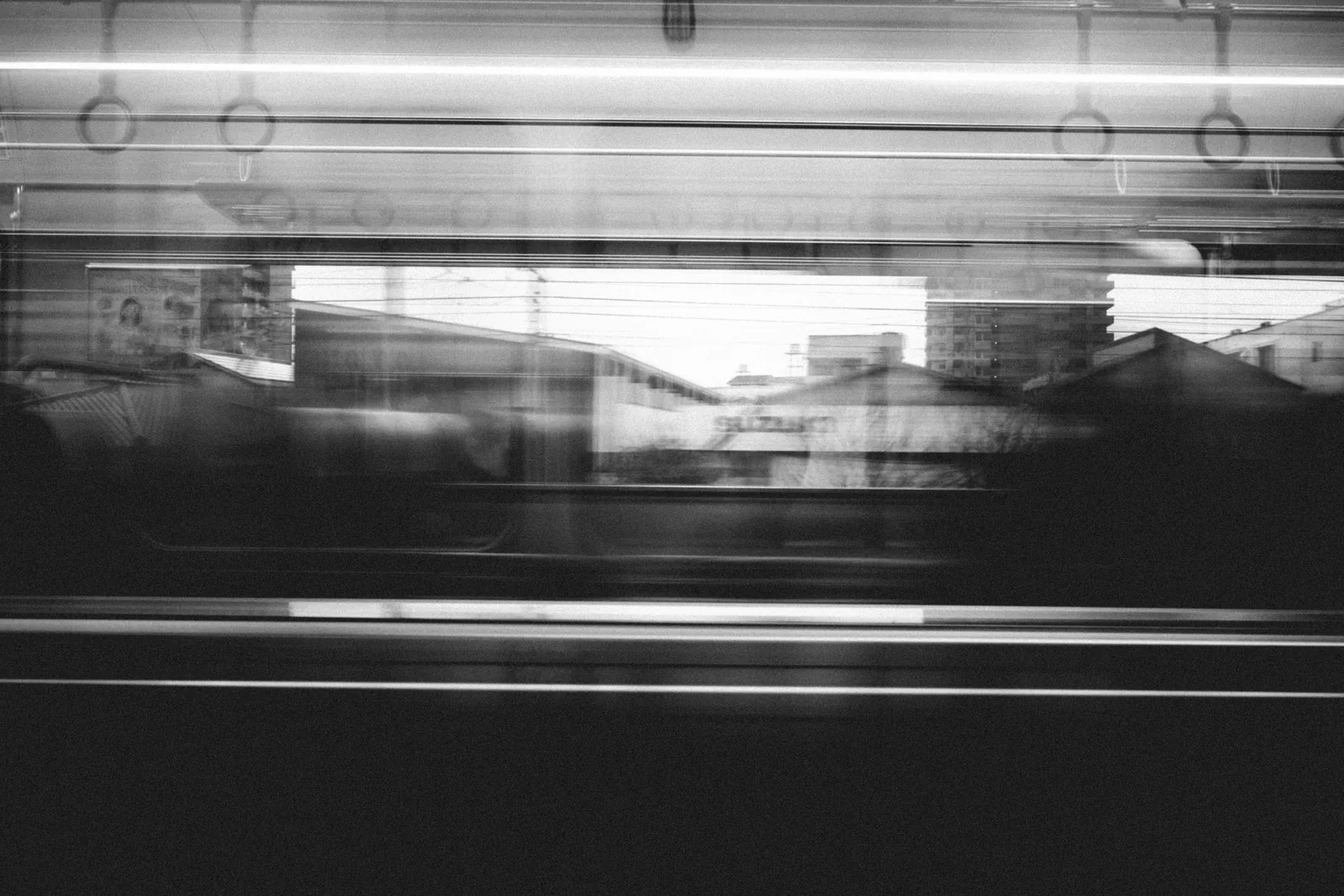 ภาพขาวดำของเมืองที่เคลื่อนผ่านหน้าต่างรถไฟอย่างพร่าเลือน